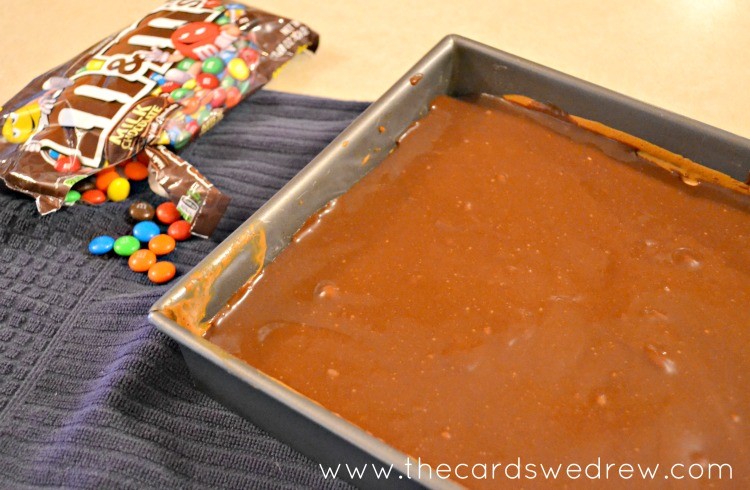 add frosting over cheesecake with pretzel crust then add m&m's